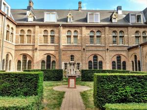 un grand bâtiment en briques avec une statue dans la cour dans l'établissement Pilgrim's Loft, à Ypres