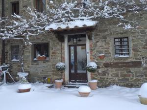 a stone building with a door covered in snow at Casina Della Burraia in Subbiano