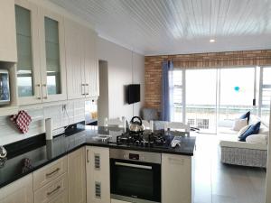 a kitchen with a stove and a living room at Surf Point 7 in Jeffreys Bay