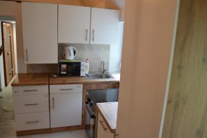 a kitchen with white cabinets and a sink and a microwave at Serendipity Spa in Kozármisleny