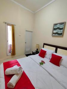 a bedroom with a large white bed with red pillows at Bakom Inn Syariah in Bogor