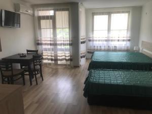 a room with two beds and a dining room with a table at GUEST HOUSE ZORNICA in OBZOR in Obzor