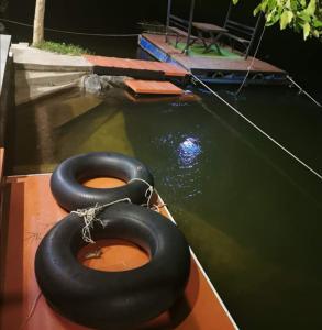 dos neumáticos negros sentados en un barco en el agua en Kaengkrachan River Hut en Kaeng Kachan