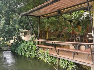 una terraza de madera con una mesa junto a un río en Kaengkrachan River Hut en Kaeng Kachan