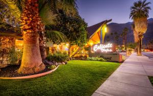 a hotel with palm trees in front of a building at Caliente Tropics in Palm Springs