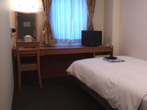 1 dormitorio con 1 cama y escritorio con TV en Natural Hot Spring Midosuji Hotel, en Osaka
