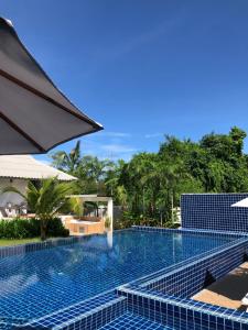 a swimming pool at a resort with an umbrella at Bulan Villa rayong in Rayong