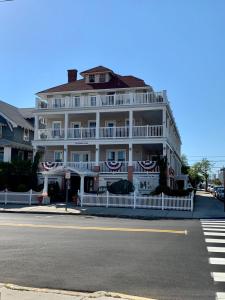 a large white building with a white fence on a street at Ocean Manor 1100 Inn in Ocean City