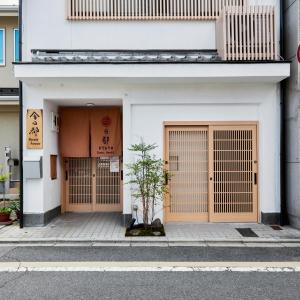 ein weißes Gebäude mit zwei Türen und einem Baum davor in der Unterkunft 今日都 Kyoto Guesthouse in Kyoto