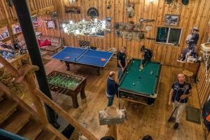 a group of people standing in a room with a pool table at lake guest ranch in Devils Tower