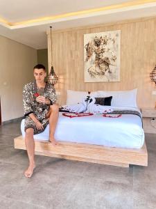 un homme assis au-dessus d'un lit dans l'établissement Ubud Hills Villas & Resort, à Ubud