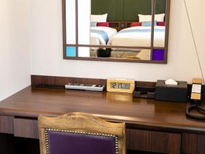 einen Schreibtisch mit einem Spiegel und ein Bett in einem Zimmer in der Unterkunft Hotel Wing International Select Ikebukuro in Tokio