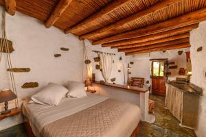 um quarto com uma cama num quarto com tectos em madeira em Natura cottages em Makry Gialos