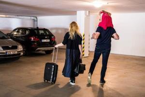 a man and woman walking through a parking lot with luggage at Apartmány Kolonáda in Luhačovice