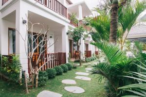 a walkway in front of a house with palm trees at La Limone Residence in Phu Quoc