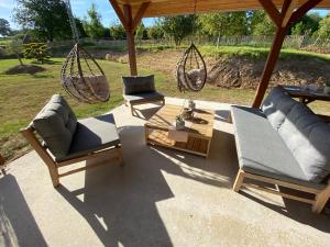 a patio with two chairs and a table and swings at Roulotte 4pers SPA Terrain multisport in Braffais