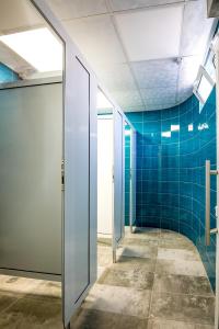d'un couloir avec des murs carrelés bleus et une porte en verre. dans l'établissement Hostel Kyosheto, à Kardjali