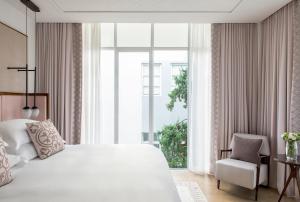 a bedroom with a large white bed and a chair at The Norman Tel Aviv in Tel Aviv