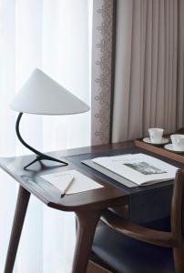 a desk with a lamp and a table with a paper at The Norman Tel Aviv in Tel Aviv