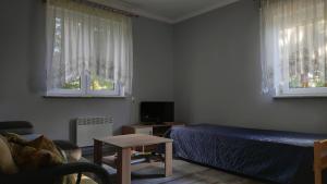 a living room with a bed and two windows at Domek Leśna Przystań in Strękowizna