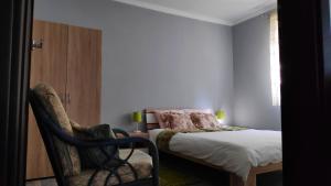 a bedroom with a bed and a chair next to a bed at Domek Leśna Przystań in Strękowizna