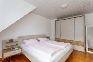 Ferienwohnung Liomena في Lehmen: غرفة نوم مع سرير بملاءات بيضاء ومخدات وردية