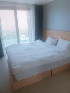 a bedroom with a white bed with a window at Sokcho Daemyung Heidi Pension in Sokcho