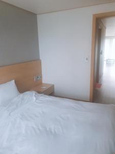a large white bed in a room with a window at Sokcho Daemyung Heidi Pension in Sokcho