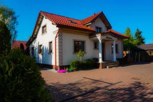 uma casa branca com um telhado vermelho numa entrada de tijolos em Hortensja em Nowa Wieś