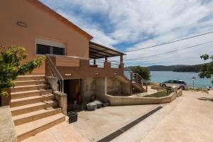 a house with stairs next to a body of water at Holiday home Nostalgija in Brgulje