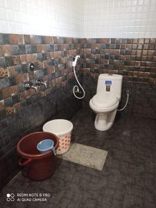 een badkamer met een toilet en een emmer bij Chuppi Homestay in Madikeri
