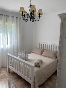ein Schlafzimmer mit einem weißen Bett und einem Kronleuchter in der Unterkunft Casa Vista Nevada in Güéjar-Sierra