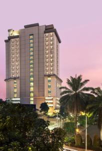 a tall building with a palm tree in front of it at Swiss-Belhotel Bogor in Bogor