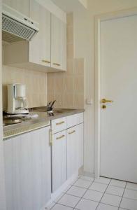 a kitchen with white cabinets and a sink and a door at Hauptallee Appartements in Bad Pyrmont