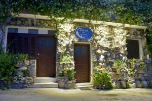 a stone building with a blue sign on it at Bella Vita Style rooms & apartments in Pitsidia