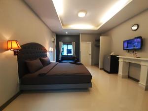 um quarto com uma cama grande e uma televisão. em Home resort em Phitsanulok