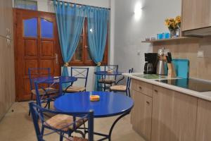 a kitchen with blue tables and chairs in a kitchen at Bella Vita Style rooms & apartments in Pitsidia