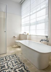 a white bath tub in a bathroom with a window at The Norman Tel Aviv in Tel Aviv