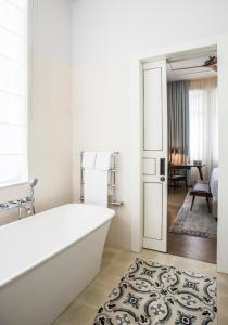 a white bathroom with a tub and a living room at The Norman Tel Aviv in Tel Aviv