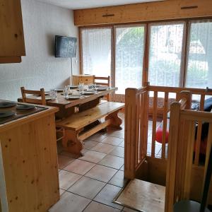 une cuisine avec une table en bois, des bancs et des fenêtres dans l'établissement Charmant appartement 6-8 personnes au cœur du village à proximité lac et pistes de ski, à Morillon