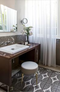 a bathroom with a sink and a stool and a mirror at The Norman Tel Aviv in Tel Aviv