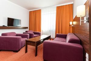 Habitación de hotel con sofás morados y TV. en Hotel Euro, en Pardubice