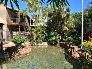 uma piscina num quintal com palmeiras em Kimberley Travellers Lodge - Broome YHA em Broome