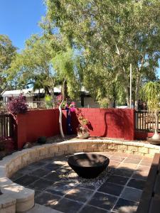 una fuente en un patio con una valla roja en Kimberley Travellers Lodge - Broome YHA, en Broome