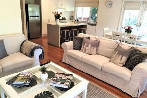 uma sala de estar com dois sofás brancos e uma mesa em Healesville House - Fig Tree House em Healesville
