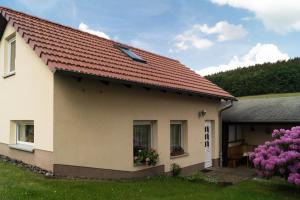 a house with a red roof and flowers in a yard at Ferienhaus Fischer in Kurort Gohrisch