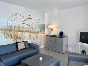 a living room with a blue couch and a tv at L'OCEAN vue bassin 1ère ligne Plage Pereire vue mer in Arcachon