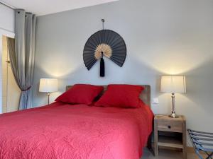 a bedroom with a red bed with a fan on the wall at L'OCEAN vue bassin 1ère ligne Plage Pereire vue mer in Arcachon