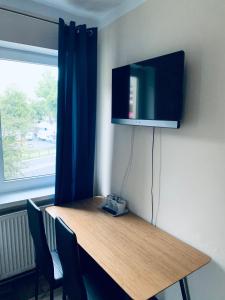 een houten tafel met een televisie aan de muur bij Pokoje Goscinne ATENA in Gubin