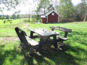 una mesa de picnic y un banco en un campo con un granero rojo en Stuga vid viltåker nära norska gränsen, en Strömstad